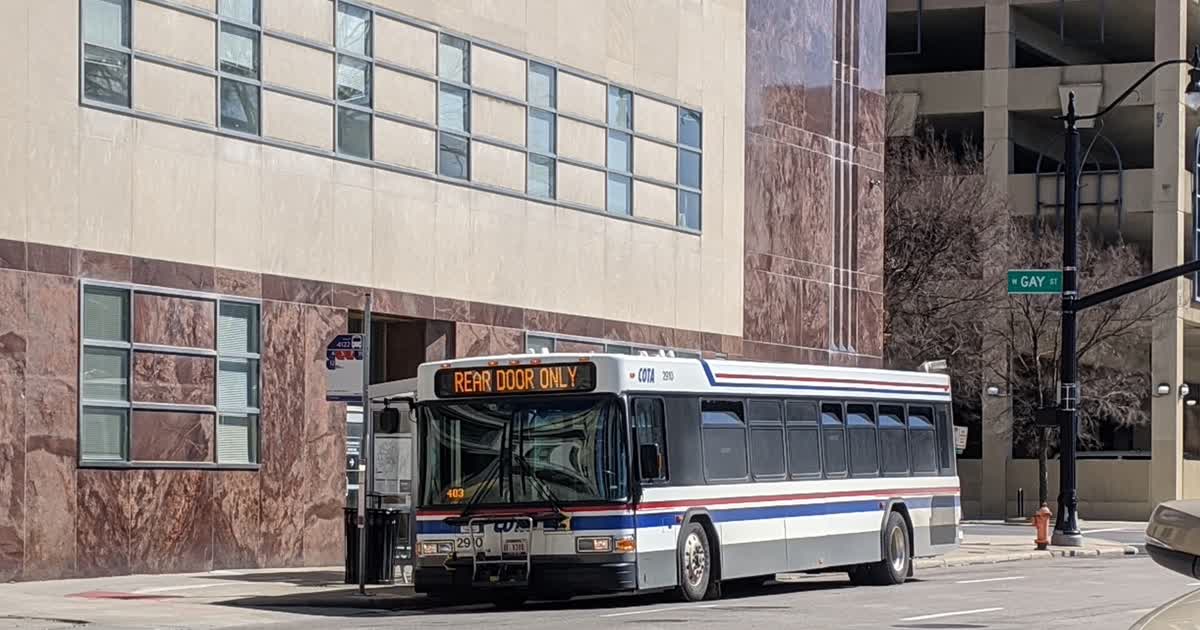 A COTA bus at a stop on a downtown Columbus street
