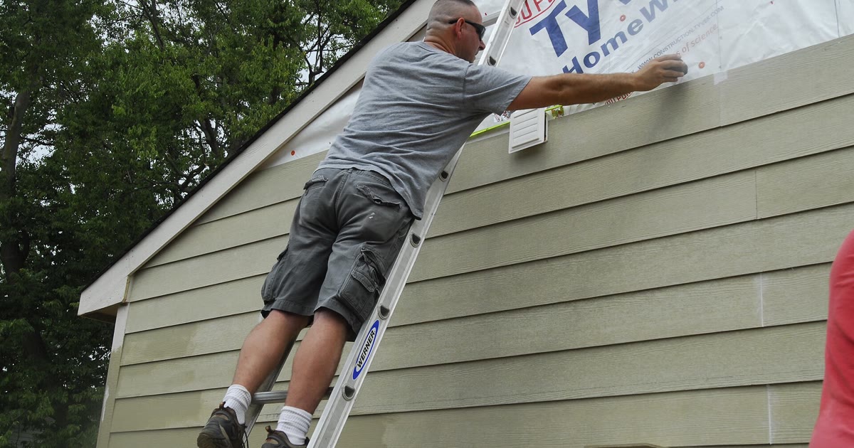Volunteer installing siding on a Habitat for Humanity home