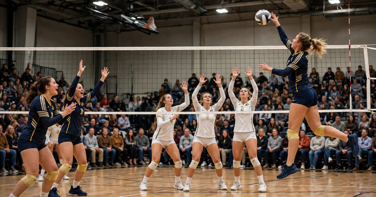A women's college volleyball player spikes the ball over the net