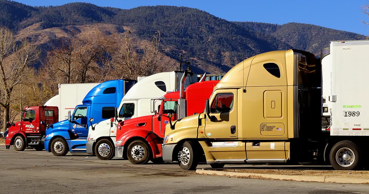 A row of semi trucks parked in a lot