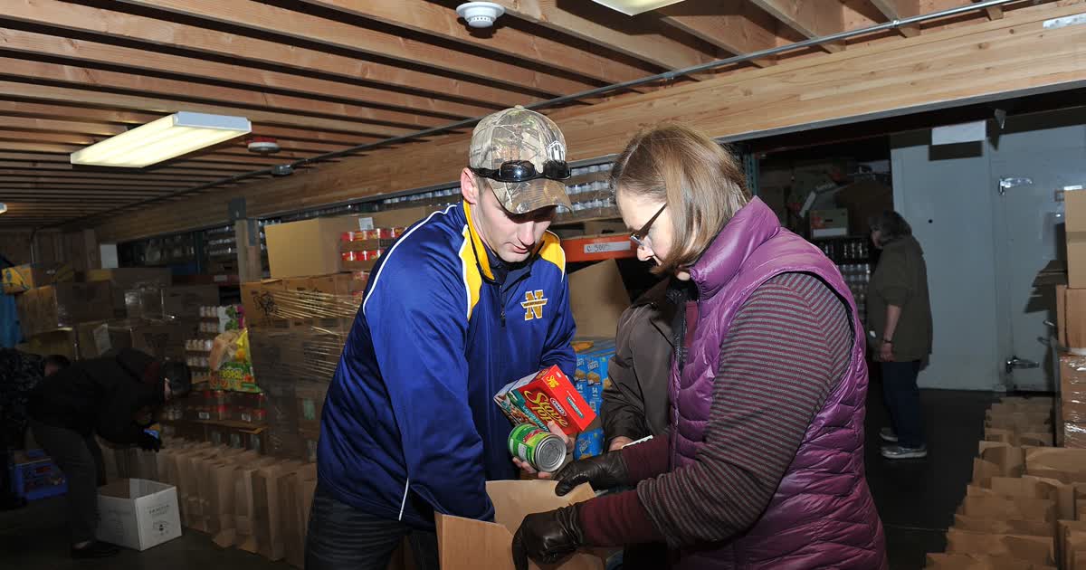 Volunteers pack grocery bags with canned food and stuffing mix at a food bank warehouse