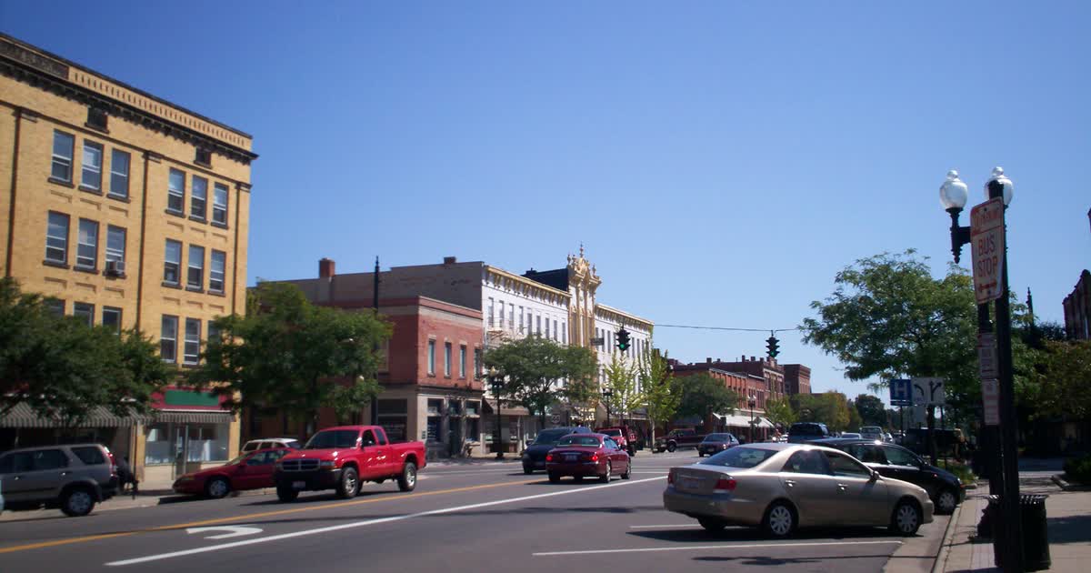 Downtown Ravenna, Ohio, along Main Street on a clear day, with traffic passing historic storefront buildings