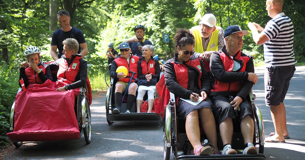 Passengers riding adaptive trishaw cycles with volunteer pilots on a park path