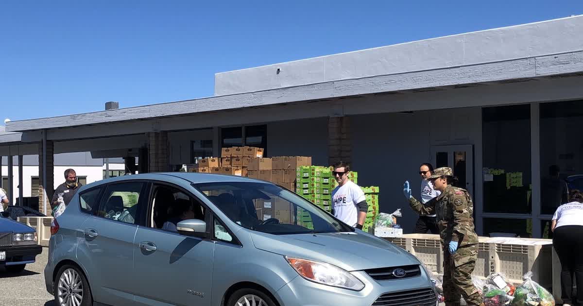 Volunteers at a drive-through food distribution with boxes of groceries