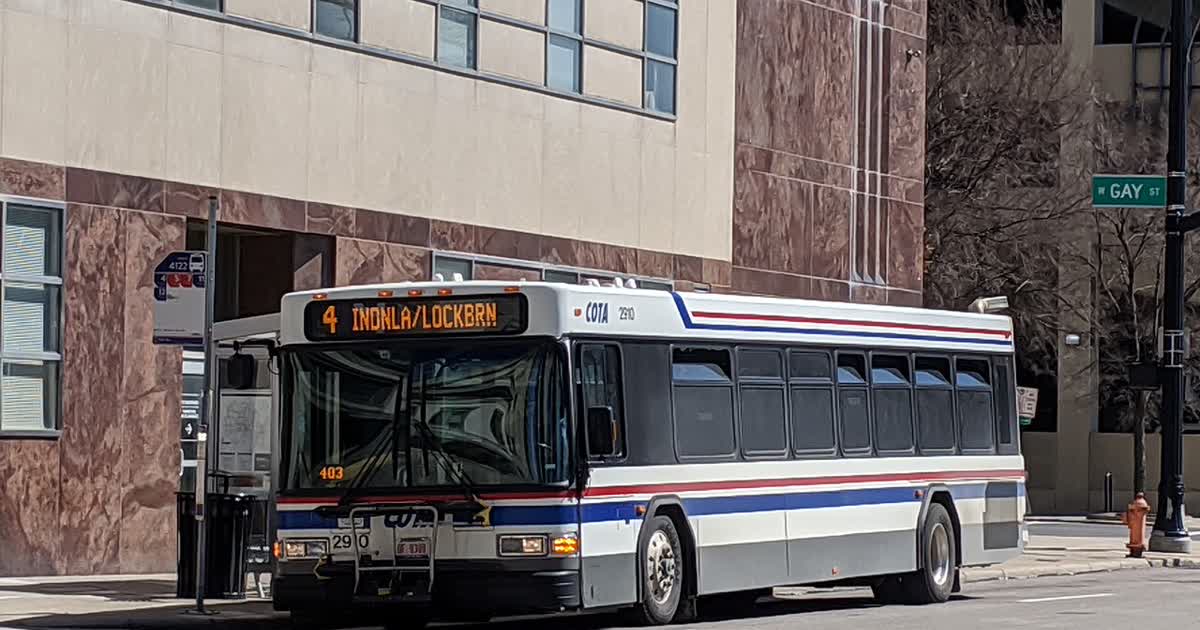 A COTA bus stopped at a bus stop on a downtown Columbus street
