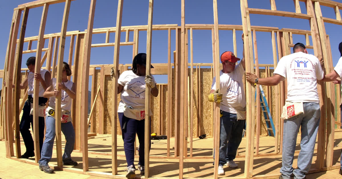 Volunteers raising a wall frame at a Habitat for Humanity home build