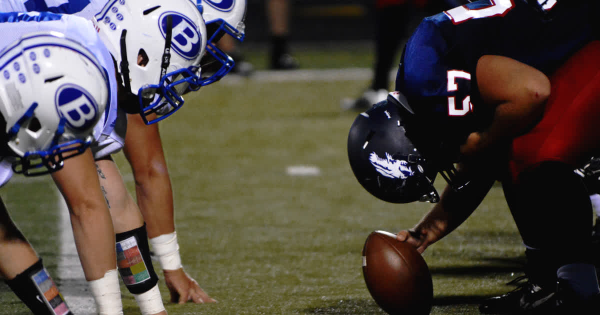 Football players at the line of scrimmage during a night game