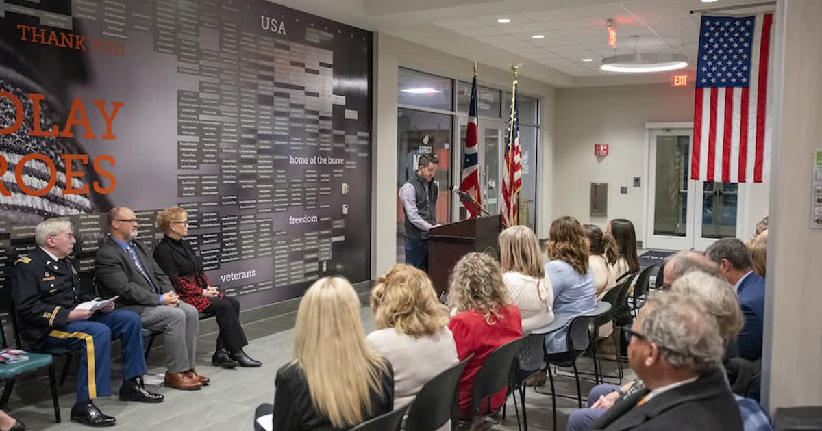 A Veterans Day ceremony at the University of Findlay Veterans Honor Wall, with an audience and flags