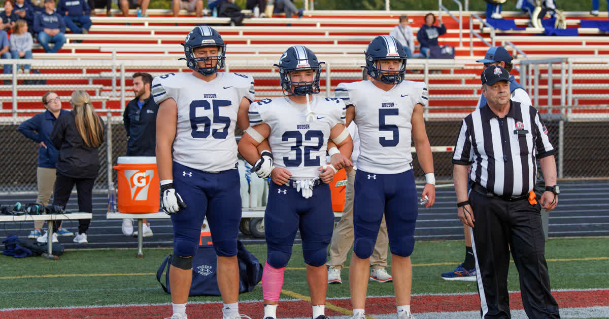 Hudson Explorers football players in white Hudson jerseys on the sideline during a game