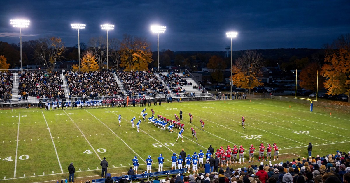 High school football teams lined up on the field under stadium lights with a packed crowd